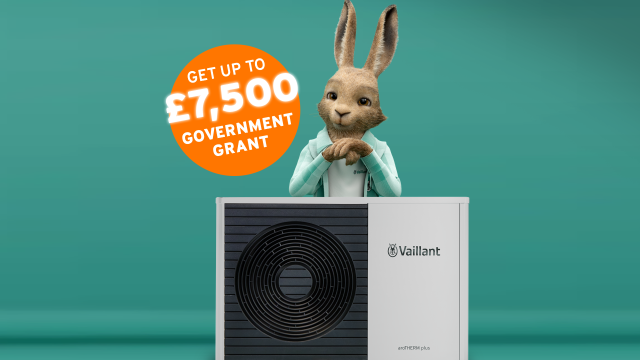 The Vaillant hare standing behind an aroTHERM plus heat pump with an orange circle sticker saying 'Get up to £7,500 government grant'