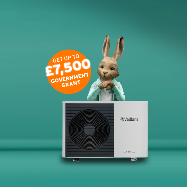 The Vaillant hare standing behind an aroTHERM plus heat pump with an orange circle sticker saying 'Get up to £7,500 government grant'