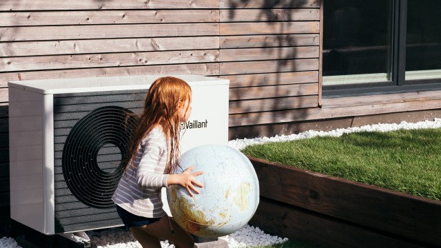 girl running in front of a heat pump with a ball in her hand