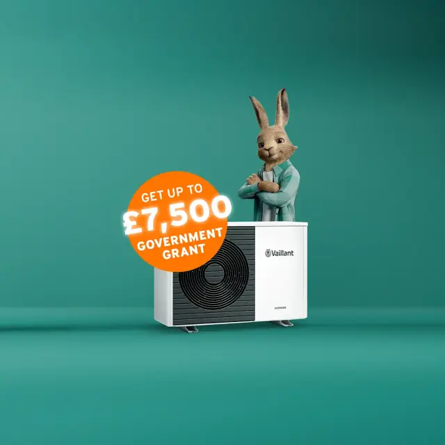 The Vaillant hare standing behind an aroTHERM plus heat pump with an orange circle sticker saying 'Get up to £7,500 government grant'