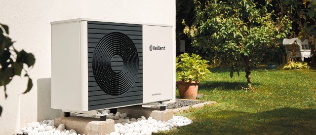 heat pump up against a white wall in a garden