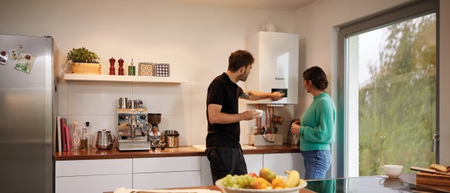 two people looking at a boiler in a kitchen