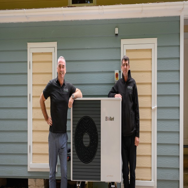 two installers leaning on a heat pump 