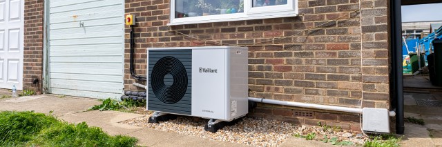 an aroTHERM plus heat pump outside a brick house