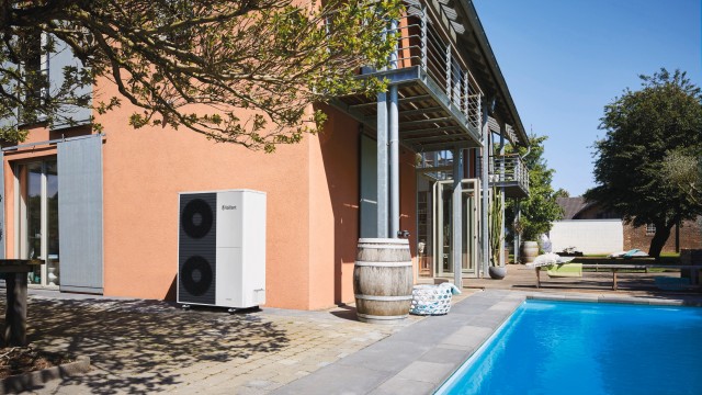 A house featuring a swimming pool and a large heat pump unit in a sunny outdoor setting.