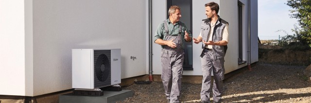 two installers walking past a vaillant heat pump 