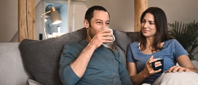 couple sat on a sofa drinking out of a mug