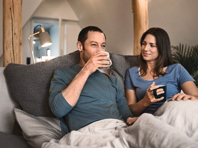 couple sat on a sofa drinking out of a mug